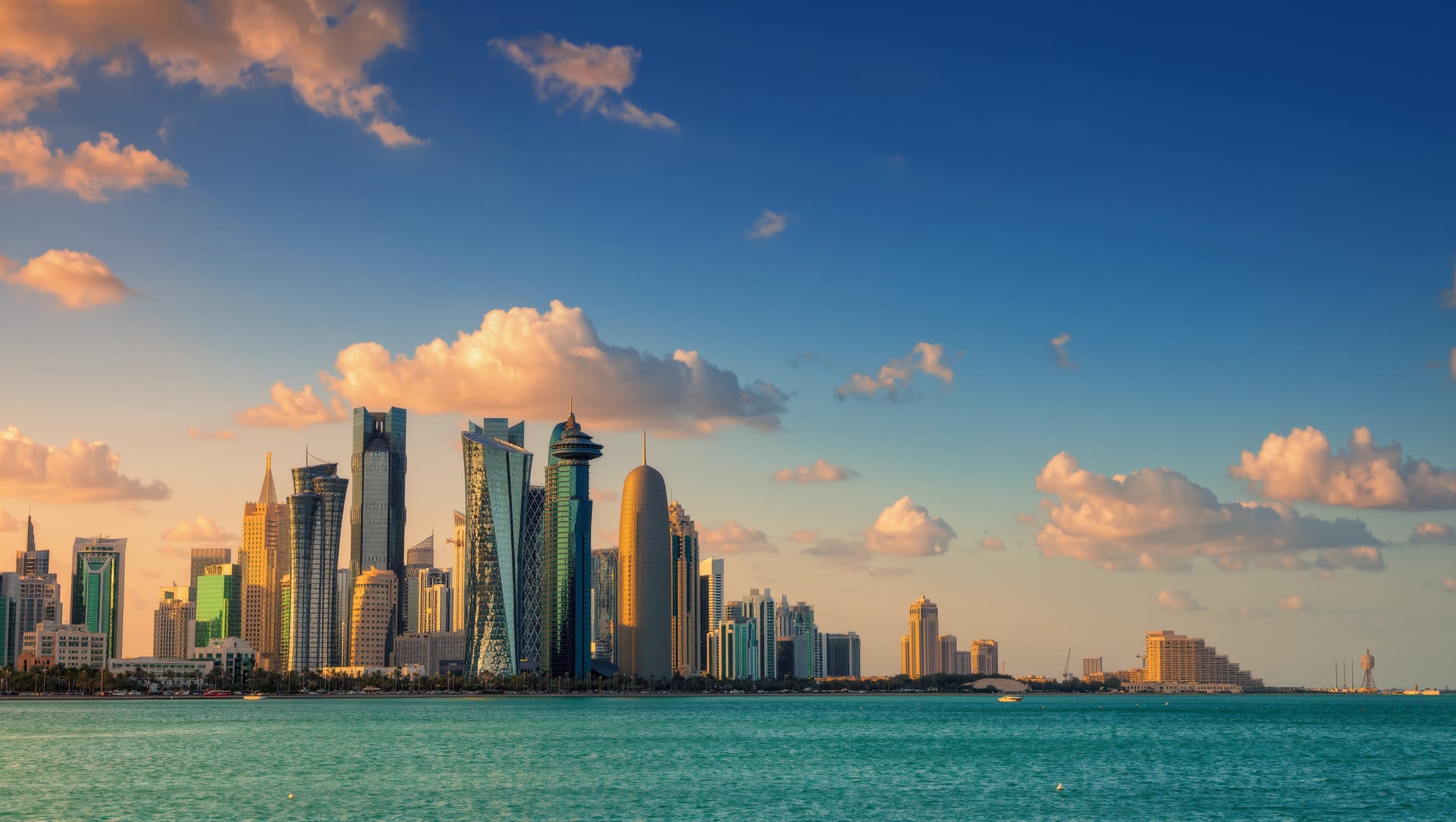 The Kuwait City waterfront skyline across turquoise water under a bright morning sky
